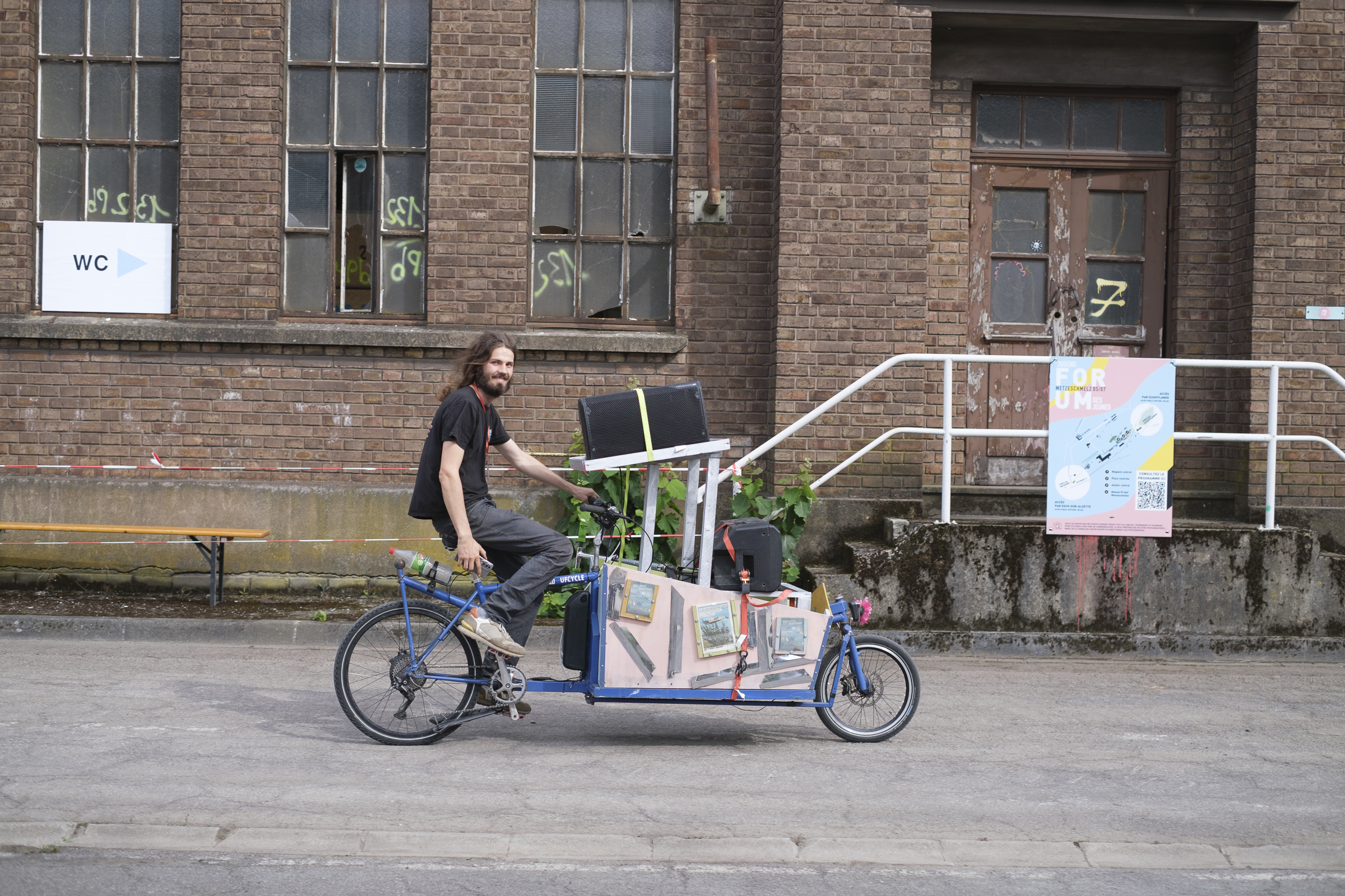 Lastenfahrrad fährt an Gebäude vorbei.